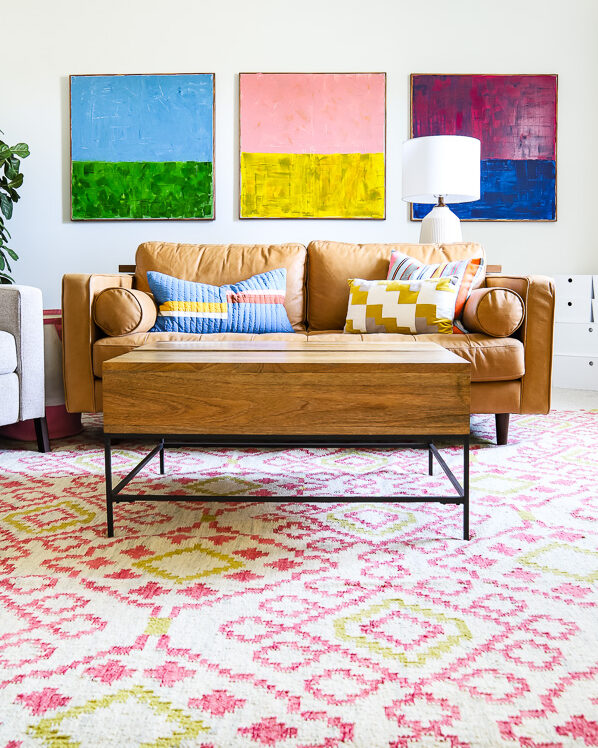colorful family bonus room with tan leather couch and colorful abstract art hanging over it