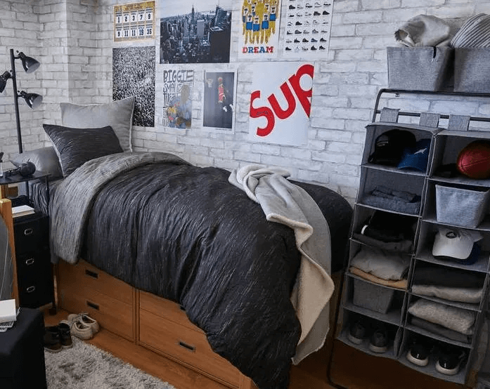boys dorm room with brick wall paper, posters, and gray bedding