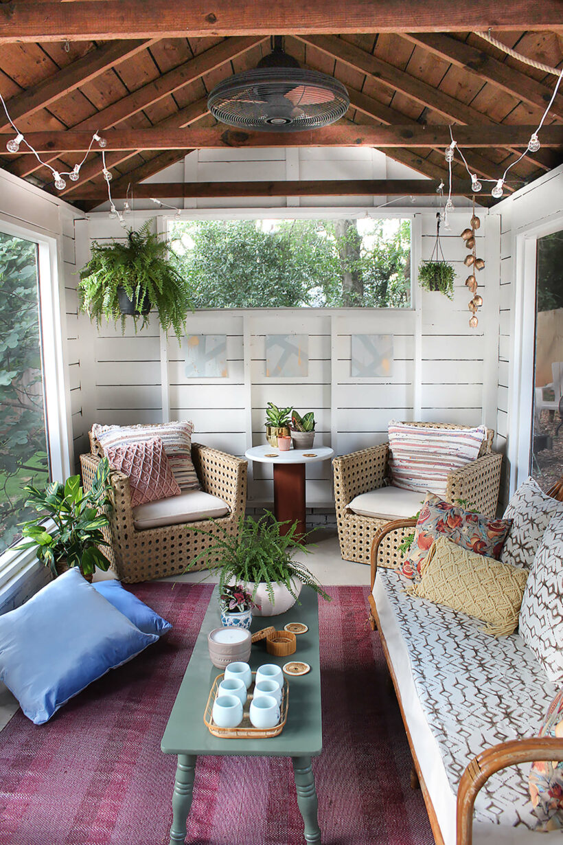 small sun room with lots of plants and eclectic furniture