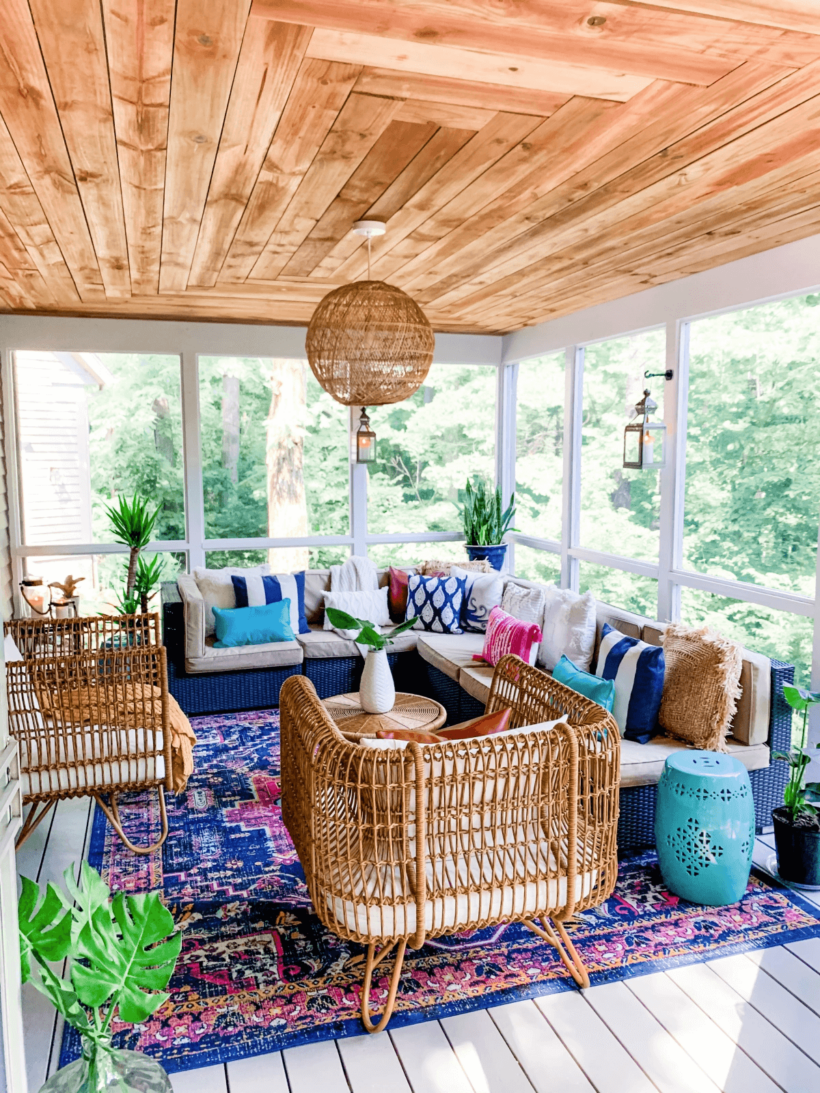 screened in porch with stained wood ceiling decorated with pinks and blues and rattan furniture