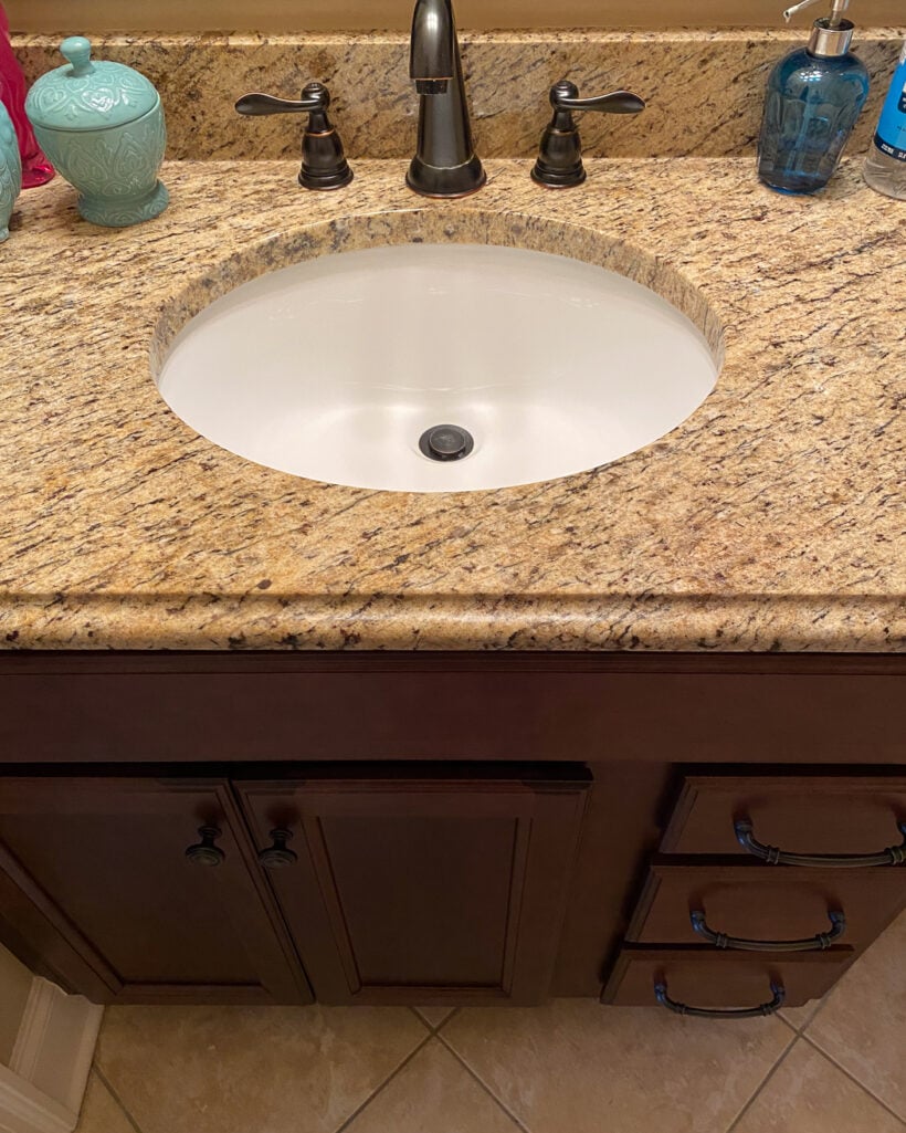 brown vanity with brown granite in outdated bathroom