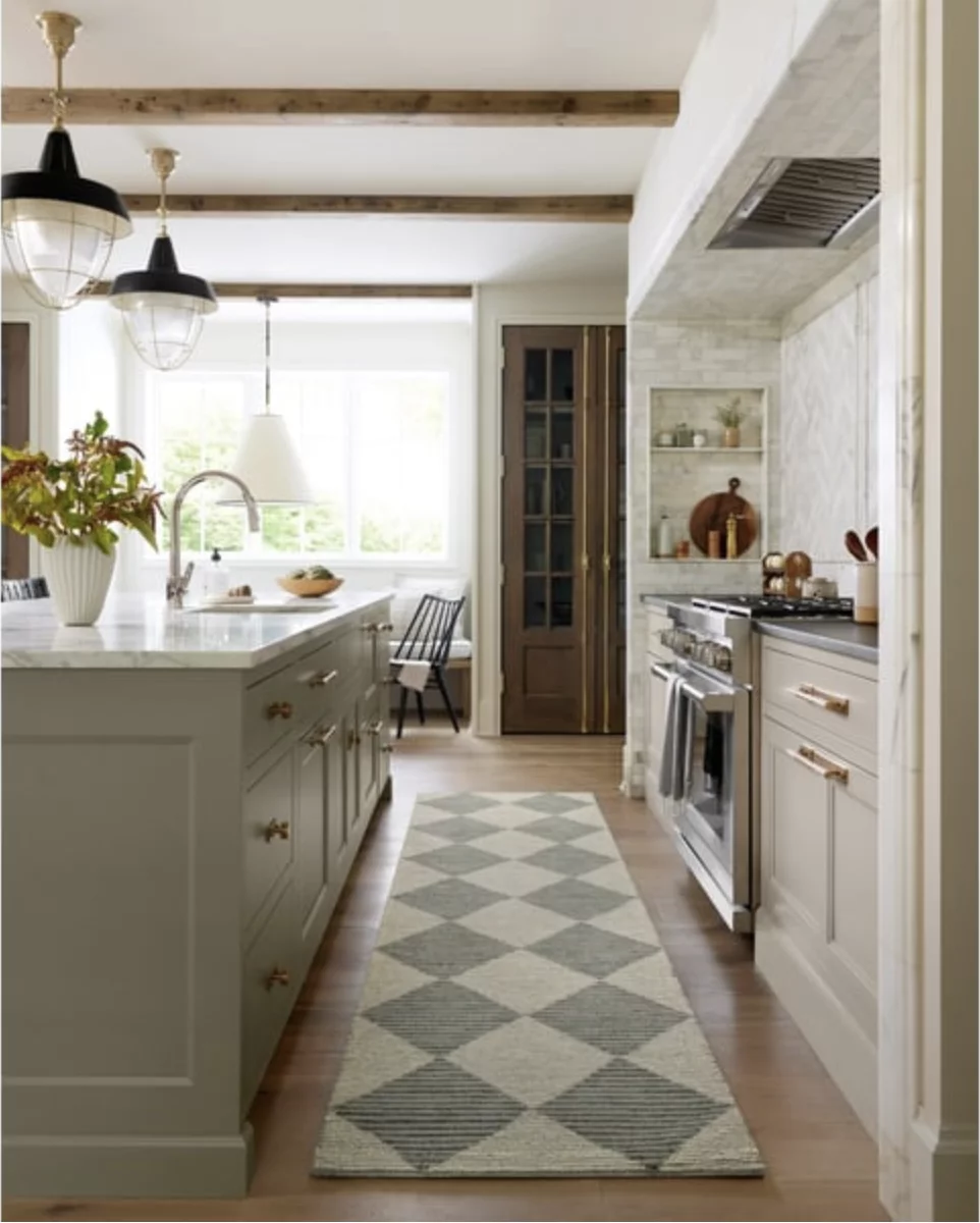 A woven diamond kitchen rug runner in large muted green and neutral kitchen lays next to the island and oven.