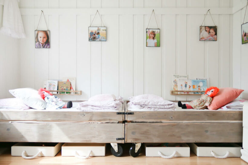 rustic wood beds on caster in white bedroom with hanging photographs over beds