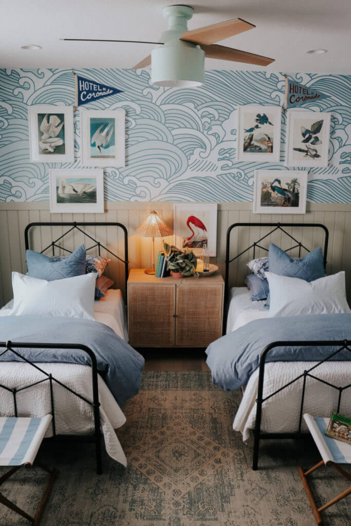 blue wave wallpaper with metal beds with blue and white bedding and bird prints over beds