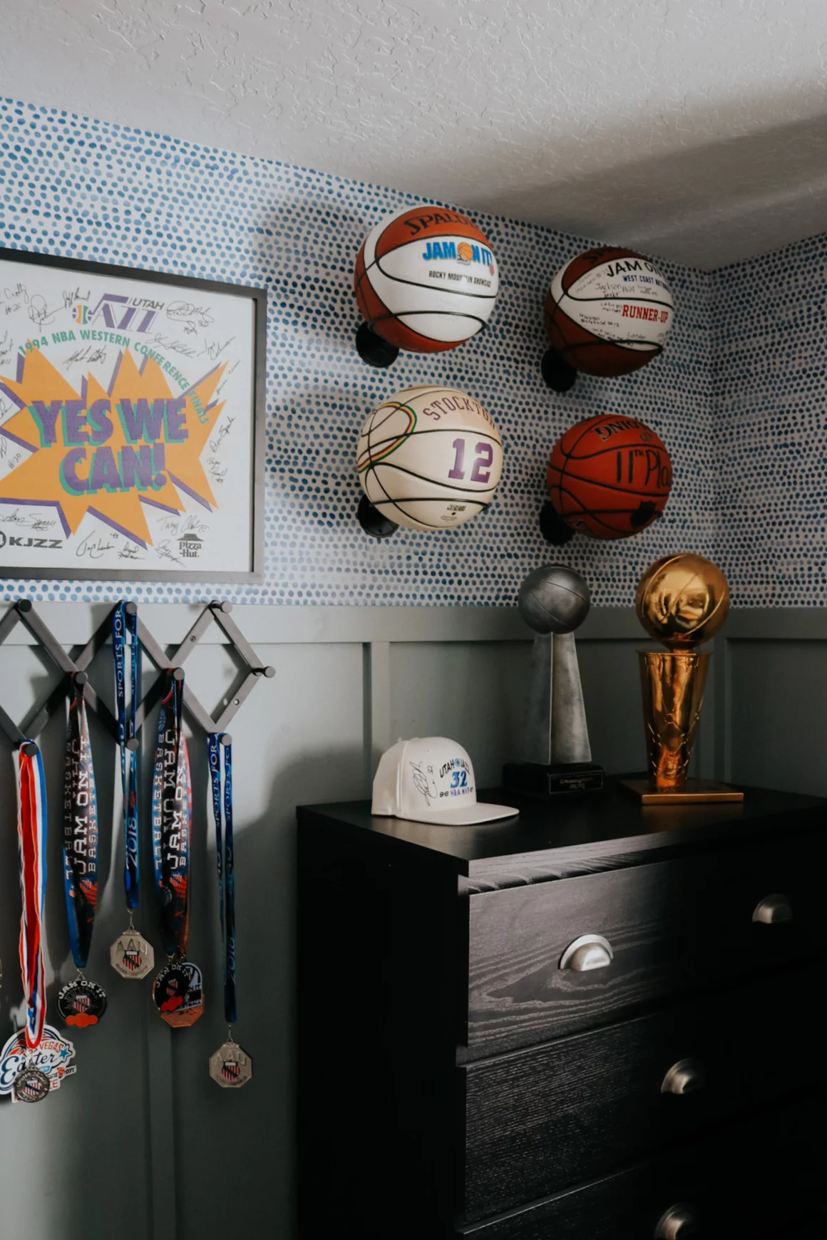 Basketballs as used wall art in teen boy's bedroom above a dark dresser and next to hanging awards. 