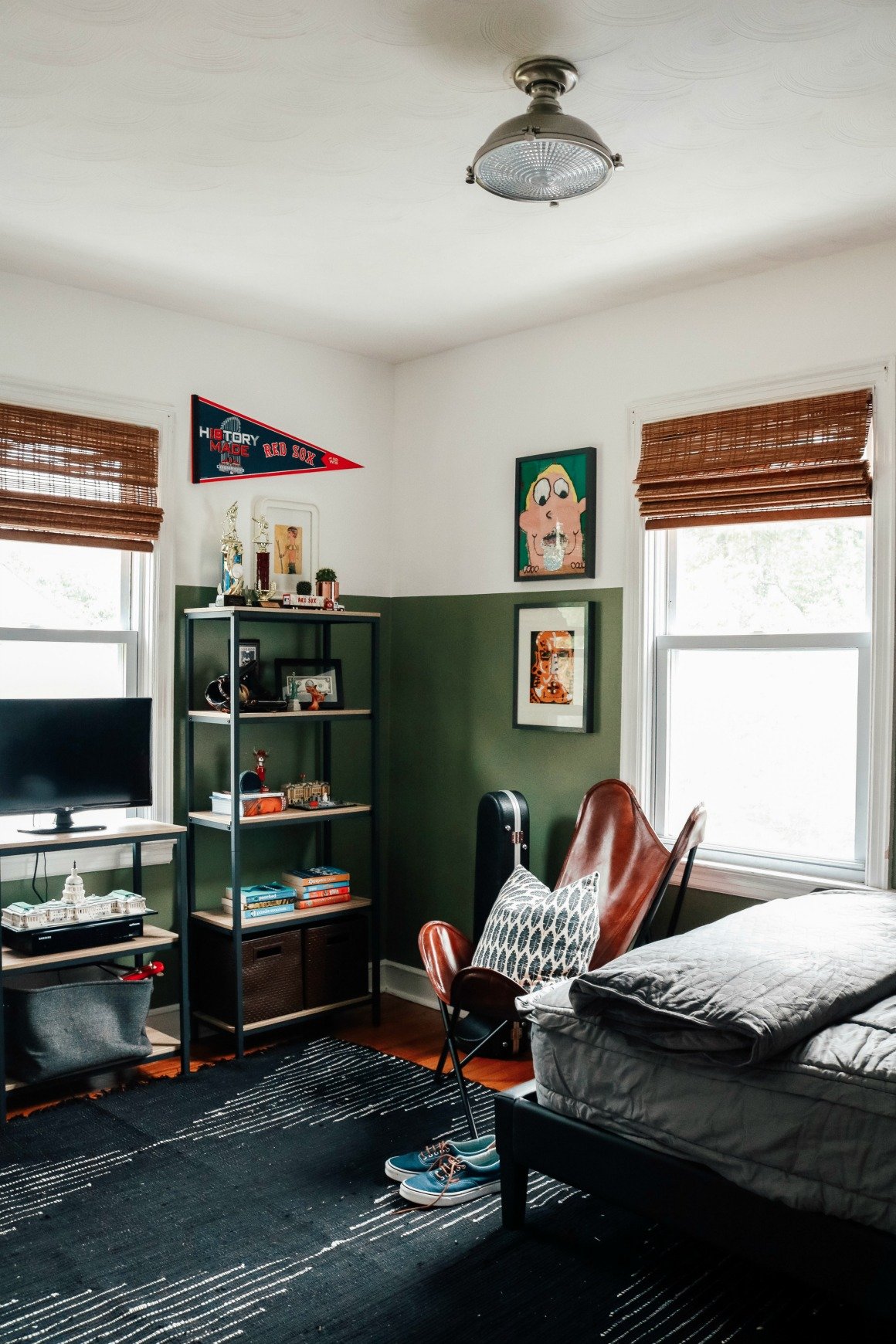 A stylish, dark green teen boy bedroom has a dedicated gaming shelf with a bookcase in the corner. 