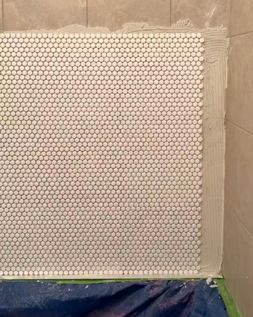 penny tiles being installed in shower over existing tiles
