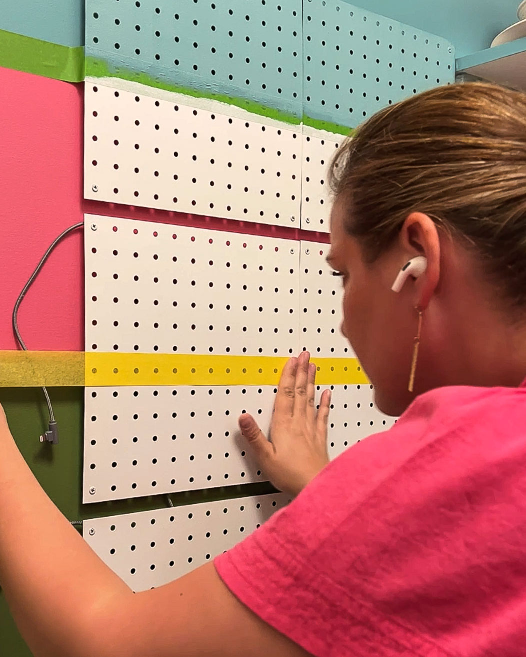woman painting metal pegboard with stripes
