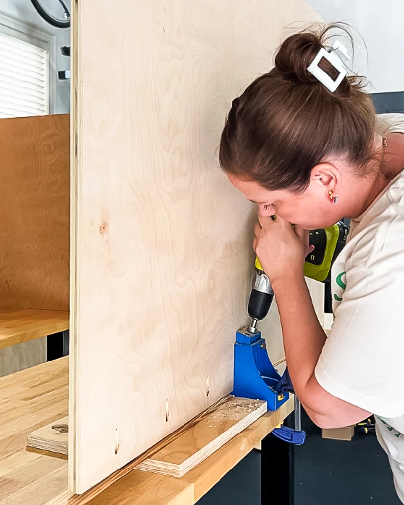 woman drilling pocket holes in plywood sheet with Kreg jig