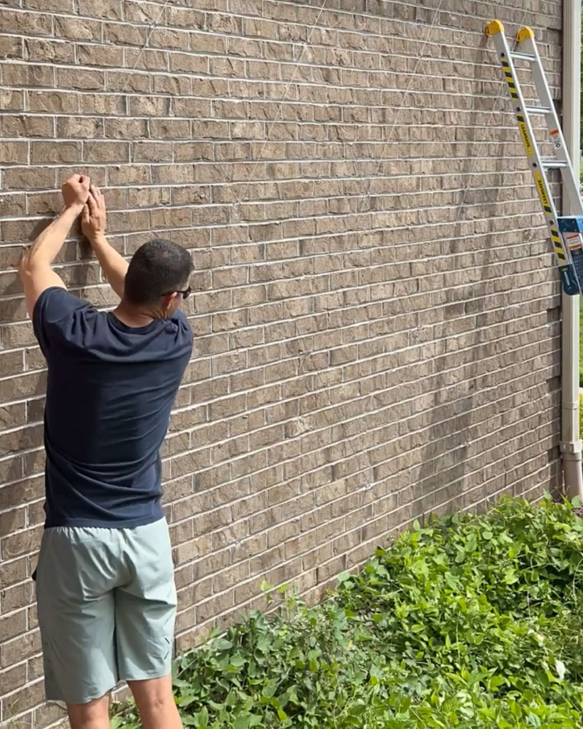 installing galvanized wire rope for trellis on exterior brick wall of home