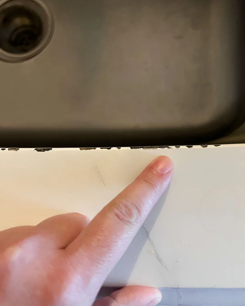 photo showing chipped countertop paint along the edge of an under-mount sink