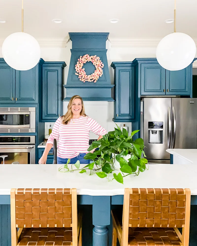 woman standing in kitchen with DIY painted cabinets and countertops