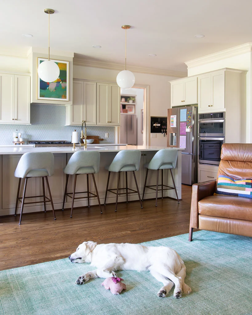 photo of great room with green rug, leather recliner and kitchen cabinets painted Accessible Beige by Sherwin Williams