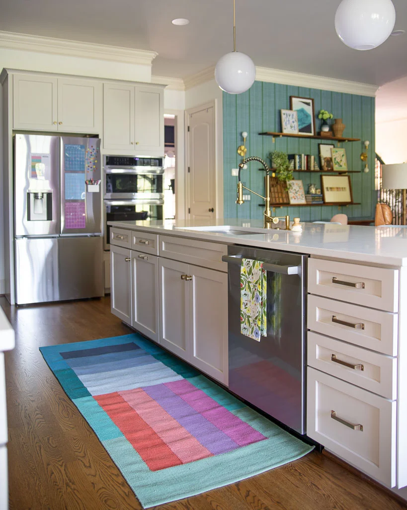 photo of kitchen with cabinets painted Accessible Beige by Sherwin Williams open to great room with colorful decor with green and blue accents