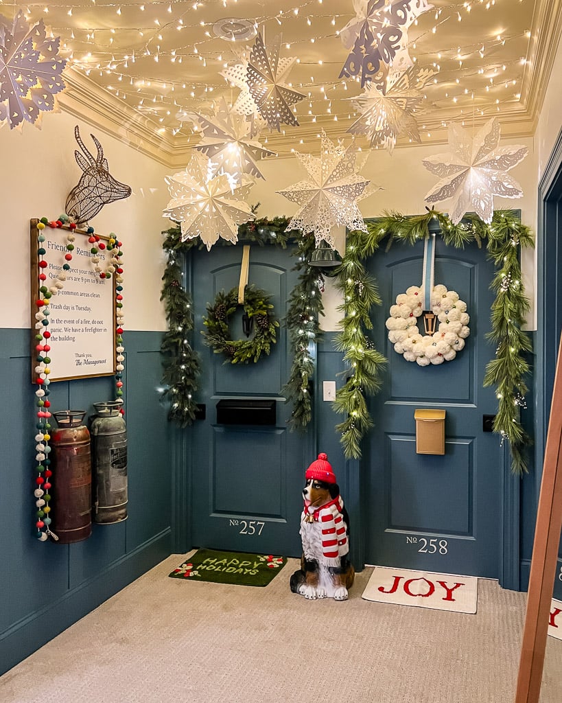 large light-up snowflake paper lanterns hanging from ceiling in hallway decorated for Christmas