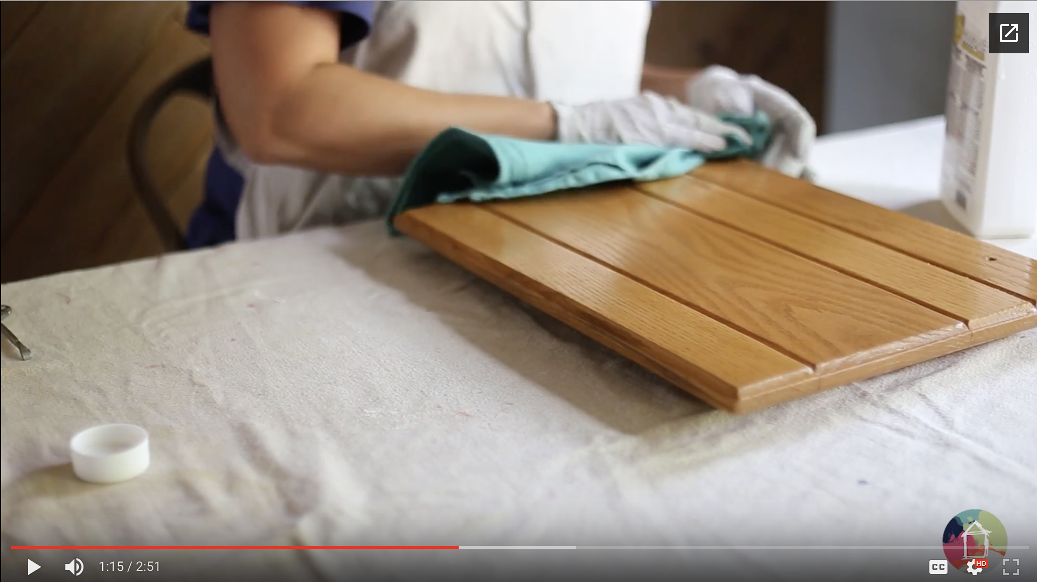 image of woman wearing latex gloves wiping down oak kitchen cabinet door with liquid deglosser
