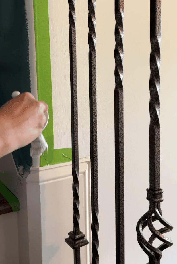 image of hand holding a paint brush and painting along the edge of painter's tape to seal it
